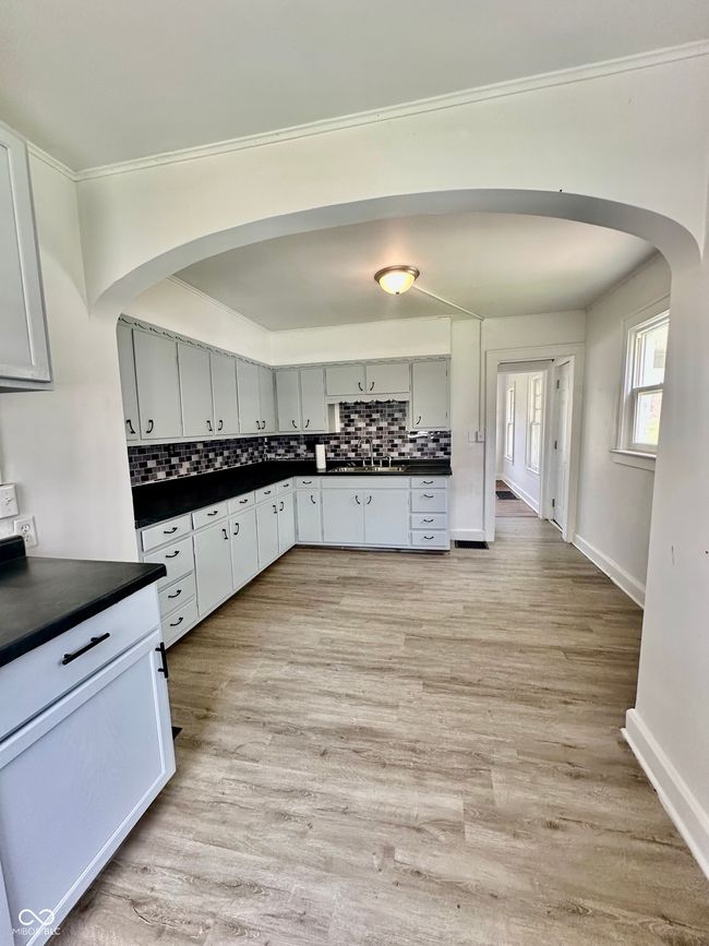 kitchen featuring decorative backsplash, dark countertops, and arched walkways | Image 28