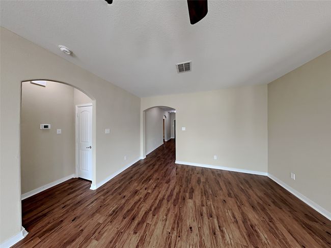 Spare room with dark wood finished floors, a smoke detector, and arched walkways | Image 9