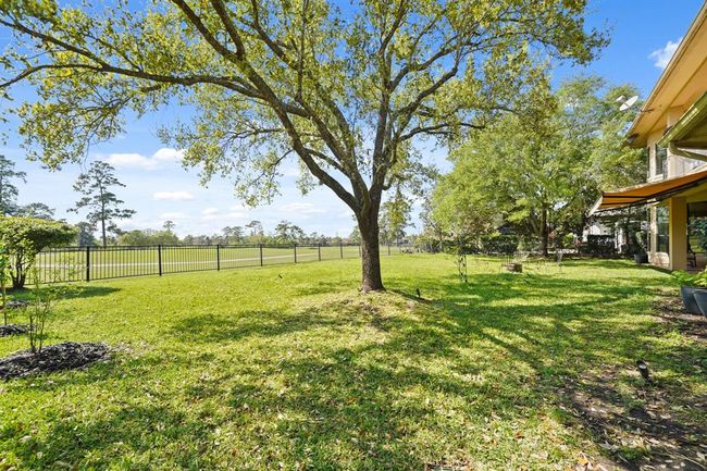 The wrought iron fenced backyard with mature shade trees offers plenty of space for child and/or pet play areas. | Image 44
