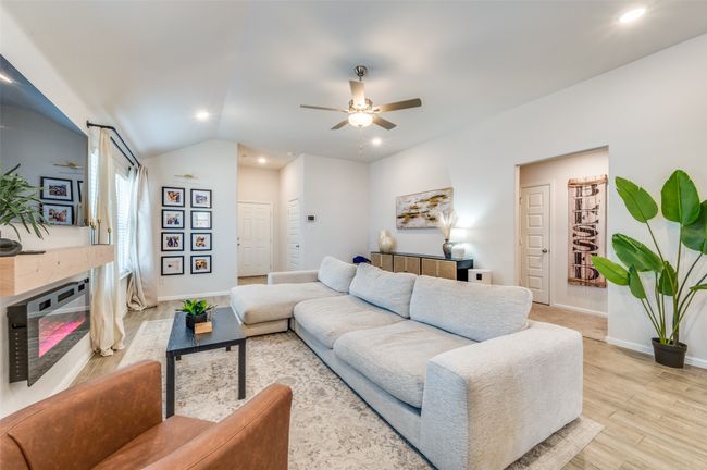 Living room with baseboards, light wood-type flooring, vaulted ceiling, recessed lighting, and ceiling fan | Image 5