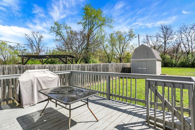 wooden terrace with a lawn, a fenced backyard, an outdoor structure, grilling area, and a storage unit | Image 37