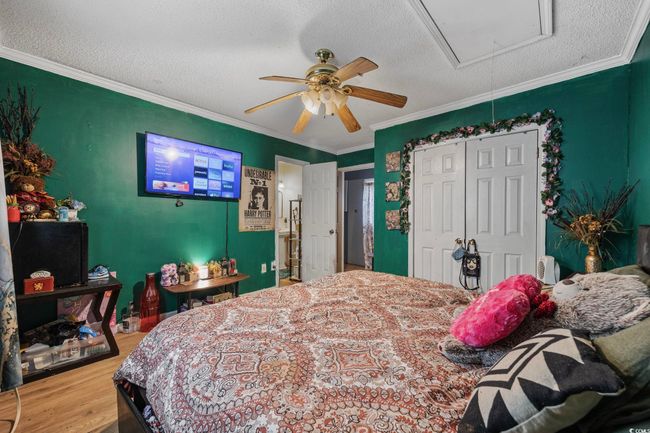 Bedroom featuring attic access, wood finished floors, ornamental molding, a closet, and a textured ceiling | Image 13