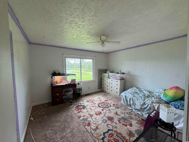 Carpeted bedroom featuring crown molding, a textured ceiling, a ceiling fan, and a desk | Image 10