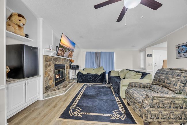 Living area with light wood-style floors, crown molding, a fireplace, ceiling fan, and a textured ceiling | Image 5