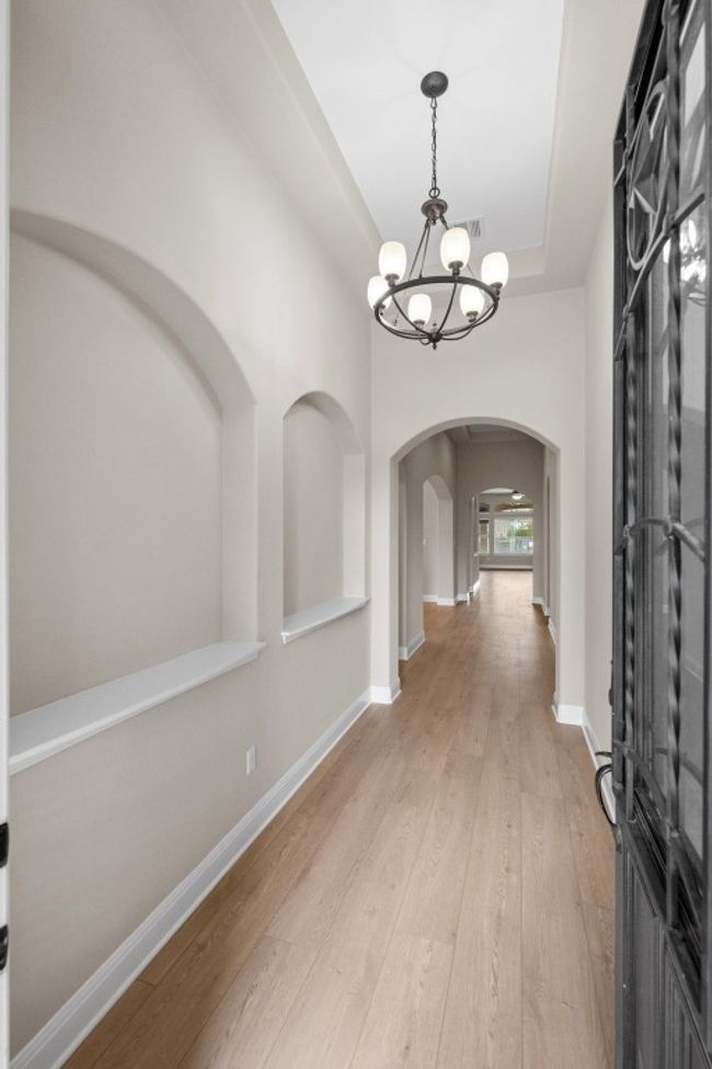Foyer featuring arched walkways, a chandelier, light wood-style flooring, and a raised ceiling | Image 4