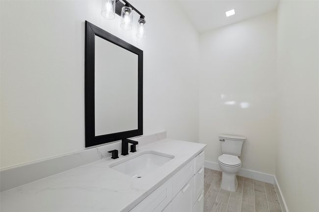 Half bath featuring toilet, vanity, baseboards, and wood tiled floor | Image 16