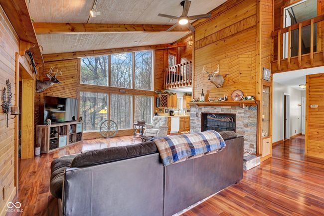 living room with warm wood walls, a towering ceiling, and ceiling fan | Image 9
