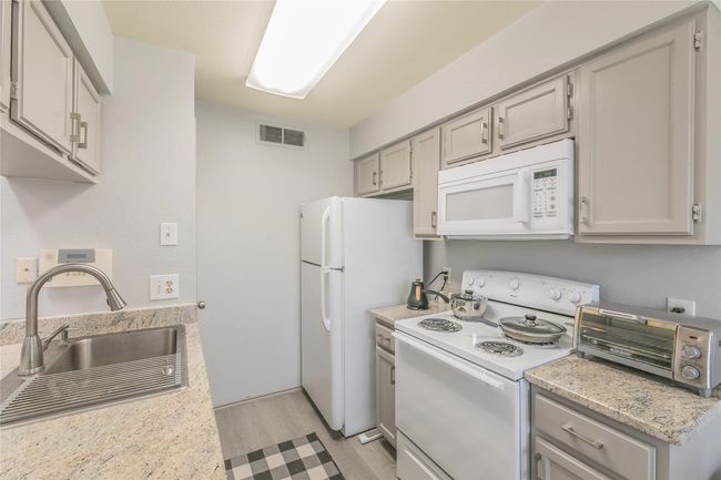 Kitchen with light hardwood / wood-style floors, sink, white appliances, and gray cabinets | Image 6