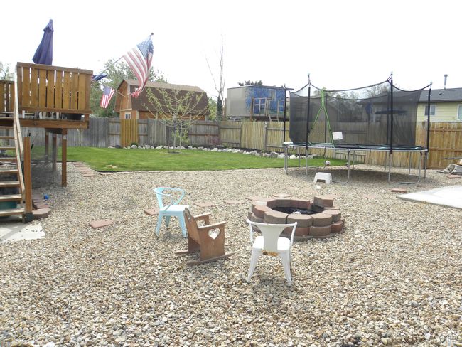View of play area featuring a trampoline, a fenced backyard, and a fire pit. | Image 37