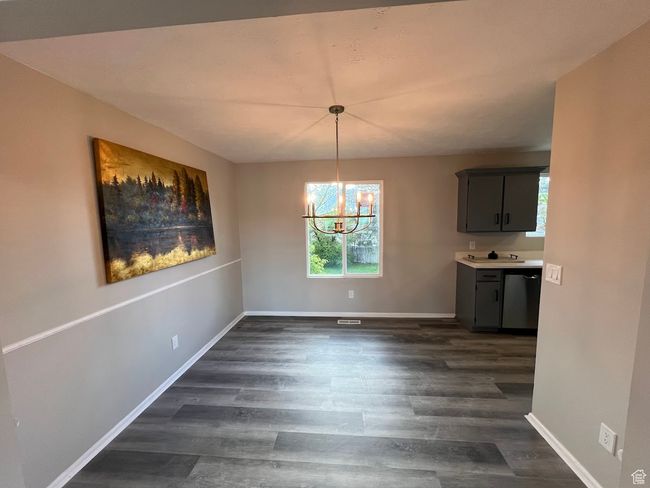 Unfurnished dining area with dark wood finished floors, baseboards, a chandelier, and plenty of natural light | Image 4