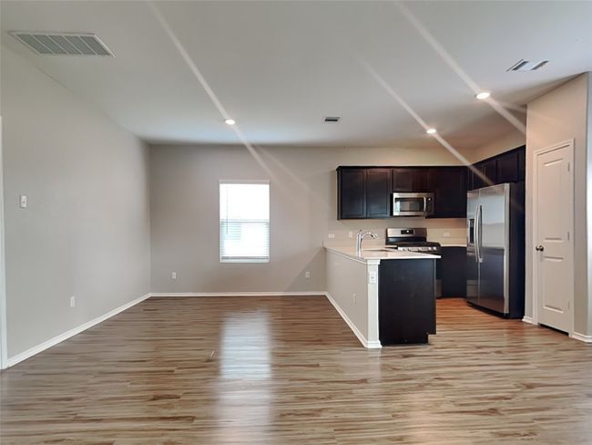 Kitchen with appliances with stainless steel finishes, light wood finished floors, light countertops, open floor plan, and baseboards | Image 4