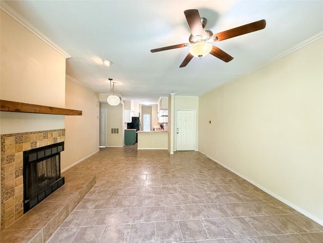 Unfurnished living room featuring a fireplace, ornamental molding, and a ceiling fan | Image 10