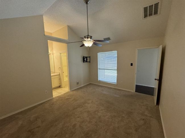 Master bedroom with ceiling fan, light tile floors, a textured ceiling, ensuite bath, and lofted ceiling | Image 12