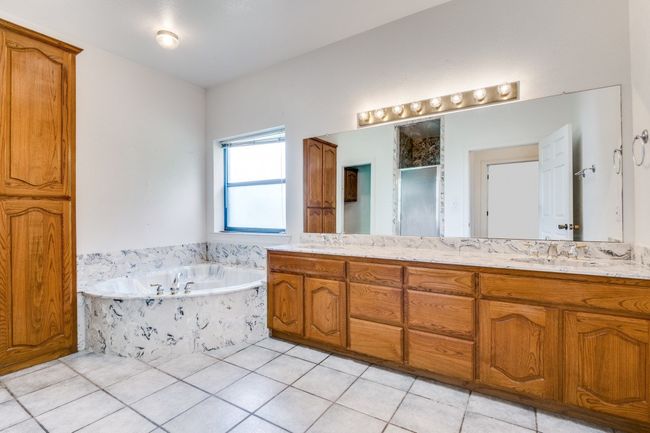Full bath featuring double vanity, a bath, a shower stall, and tile patterned flooring | Image 13