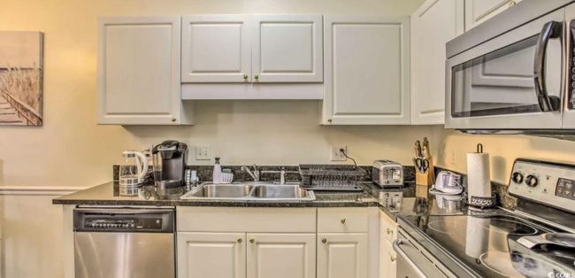 Kitchen with appliances with stainless steel finishes, dark countertops, and white cabinetry | Image 12