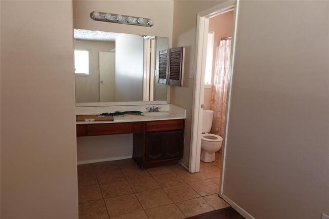 Spacious master bedroom with en-suite bathroom, featuring a large vanity and natural light. | Image 12