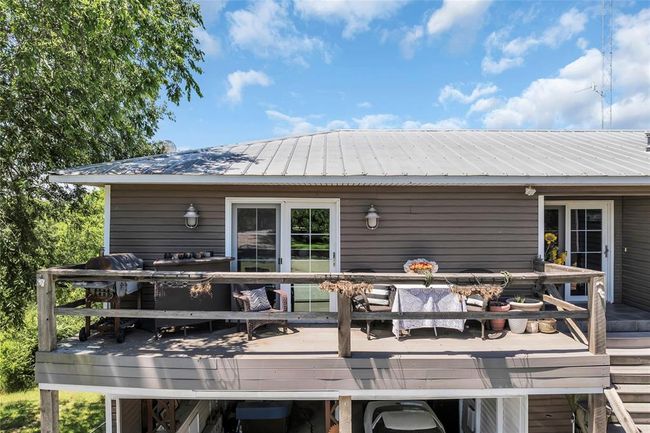 Rear view of house featuring a wooden deck, outdoor dining area, and metal roof | Image 46