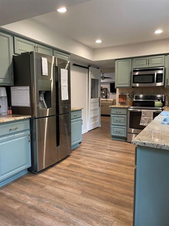 Kitchen with appliances with stainless steel finishes, light wood-style floors, tasteful backsplash, recessed lighting, and light granite countertops | Image 5