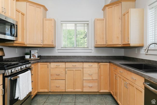 Kitchen featuring appliances with stainless steel finishes, light brown cabinetry, dark countertops, and tile patterned flooring | Image 8