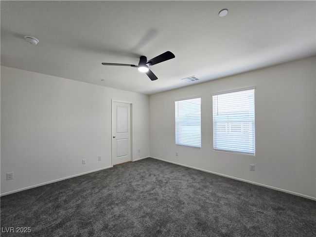 Empty room featuring a ceiling fan, dark colored carpet, a smoke detector, and baseboards | Image 29