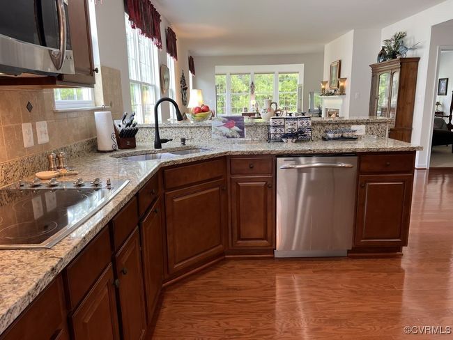 Kitchen featuring light stone countertops, appliances with stainless steel finishes, dark wood-type flooring, and sink | Image 19
