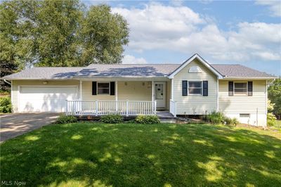 Ranch-style house featuring a garage, covered porch, and a front yard | Image 1