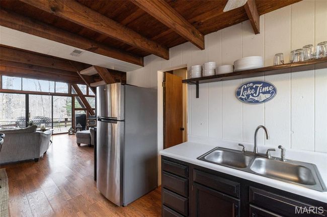 Kitchen with dark wood finished floors, beam ceiling, freestanding refrigerator, a sink, and wooden ceiling | Image 17