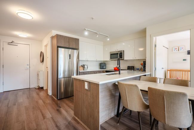 Kitchen featuring appliances with stainless steel finishes, a breakfast bar area, light countertops, tasteful backsplash, and white cabinetry | Image 9