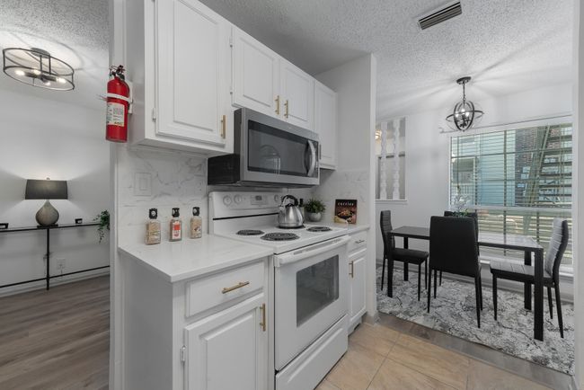 Kitchen featuring stainless steel microwave, a chandelier, a textured ceiling, and white range with electric stovetop | Image 20