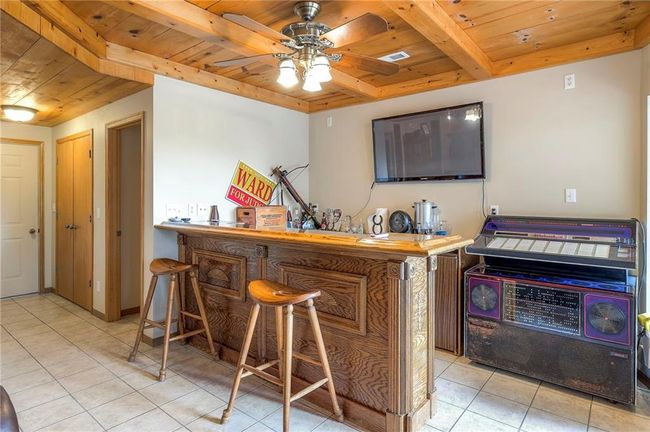 Indoor dry bar with a wooden ceiling with exposed beams, light tile patterned flooring, and ceiling fan | Image 34