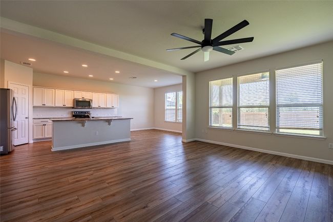 Unfurnished living room with dark wood finished floors, a ceiling fan, and recessed lighting | Image 4