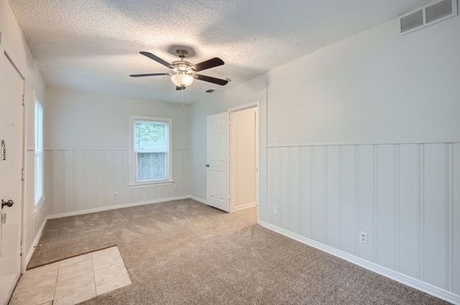 Unfurnished bedroom featuring visible vents, a wainscoted wall, a textured ceiling, and carpet | Image 18