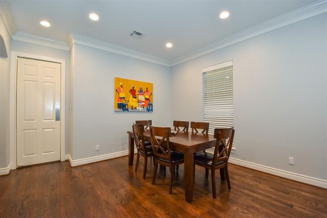 Spacious dining room with hardwood floors, crown molding, recessed lighting, a large window for natural light - door leads to the kitchen | Image 6