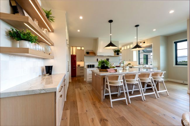 Kitchen featuring open shelves, a spacious island, light wood-type flooring, a breakfast bar area, and recessed lighting | Image 16