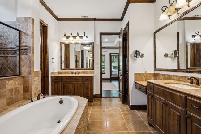Bathroom featuring crown molding, a bath, two vanities, tiled shower, and tile patterned flooring | Image 8
