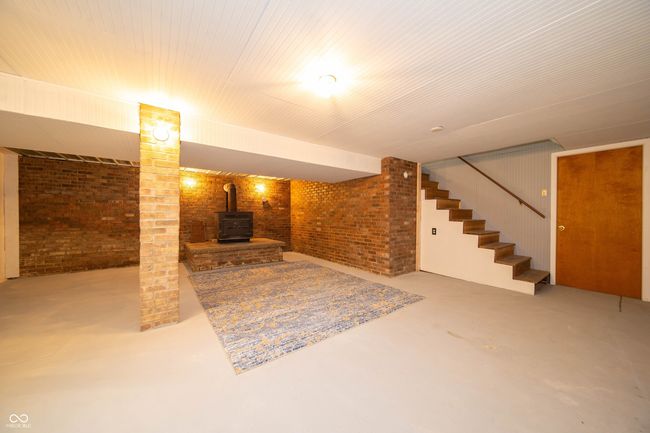 finished below grade area with brick wall, stairway, and a wood stove | Image 27