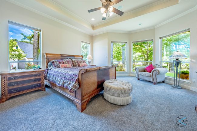 Carpeted bedroom featuring a tray ceiling, ornamental molding, and ceiling fan | Image 13