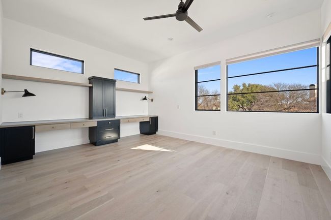Unfurnished office featuring baseboards, built in desk, a ceiling fan, and light wood-style floors | Image 28