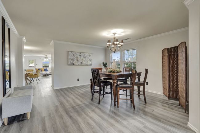 Dining space featuring light hardwood / wood-style flooring, crown molding, and ceiling fan with notable chandelier | Image 8