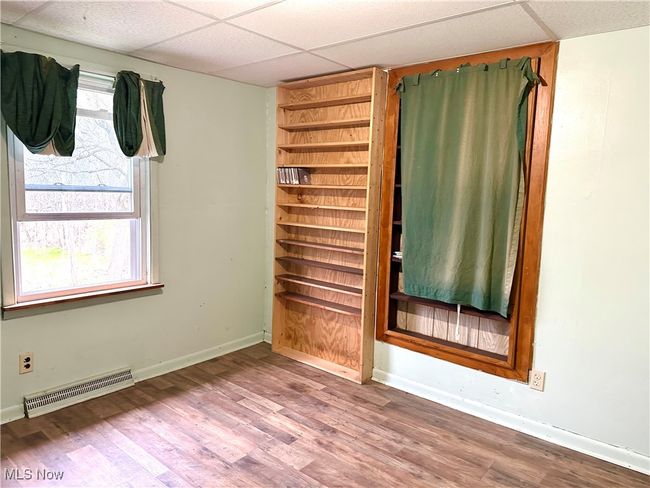 Unfurnished room featuring a drop ceiling, wood finished floors, visible vents, and baseboards | Image 13