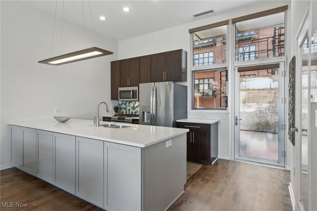 Kitchen with a peninsula, dark wood-style floors, a sink, visible vents, and appliances with stainless steel finishes | Image 13