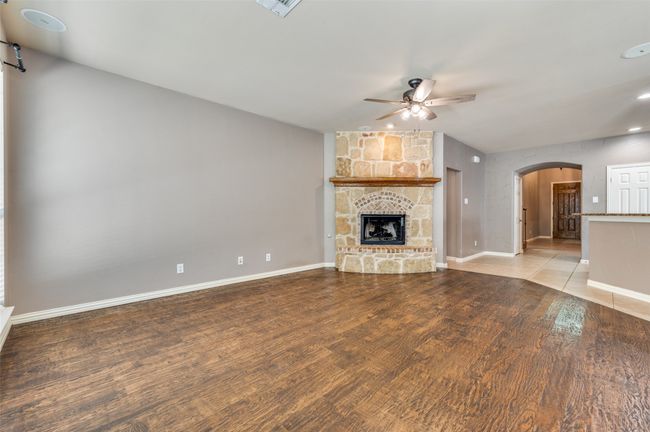Family Room featuring ceiling fan, handscraped wood finished floors, and a stone fireplace with hearth | Image 5