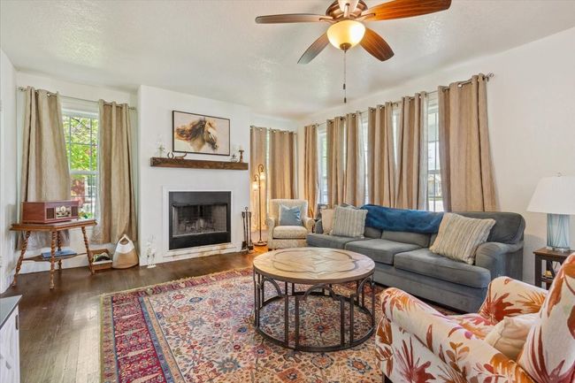 Living area with a fireplace, a textured ceiling, wood finished floors, and ceiling fan | Image 5