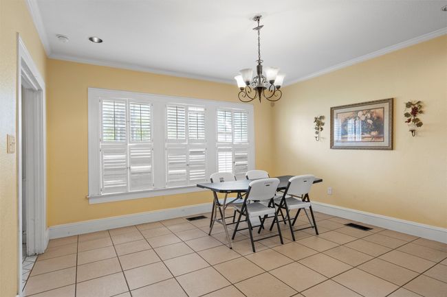 Dining room with ornamental molding, light tile patterned floors, and a chandelier | Image 7