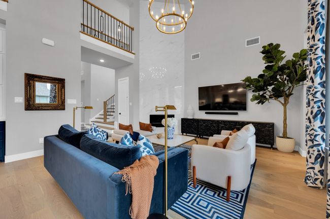 Living room with a high ceiling, stairs, wood finished floors, and a chandelier | Image 11