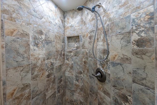The walk-in shower in the second bathroom has custom floor-to-ceiling tiles in various layouts & | Image 24