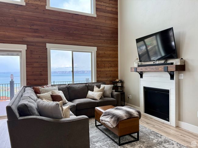 Living room with a high ceiling, wooden walls, a fireplace, and a healthy amount of sunlight | Image 18