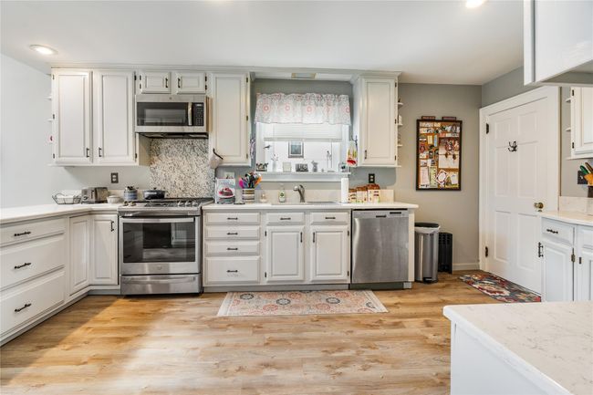 Kitchen with white cabinets, light countertops, a sink, light wood-style floors, and appliances with stainless steel finishes | Image 10