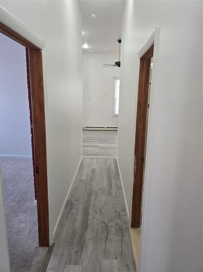 Hall featuring baseboard heating, wood finished floors, and baseboards | Image 12