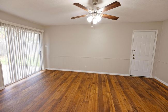 Unfurnished room with wood finished floors, a ceiling fan, and baseboards | Image 11